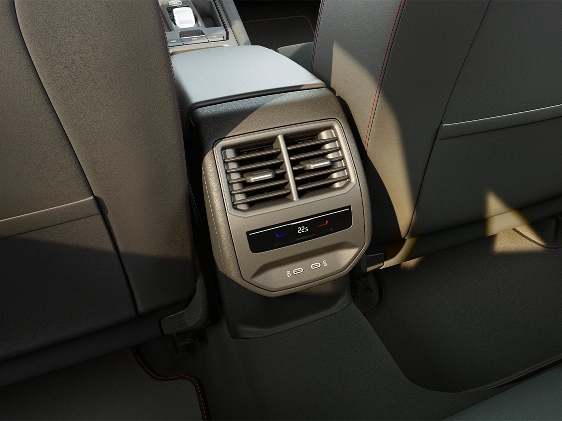 Vue intérieure arrière présentant le pack Confort de la SEAT Leon avec climatisation Climatronic à 3 zones, des prises USB-C et un accoudoir central.