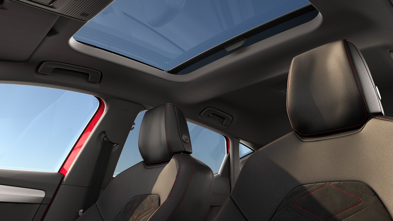 Vue intérieure d’une seat avec toit ouvrant panoramique et passager vêtu d’une tenue rouge vif, montrant le design spacieux de l’habitacle.
