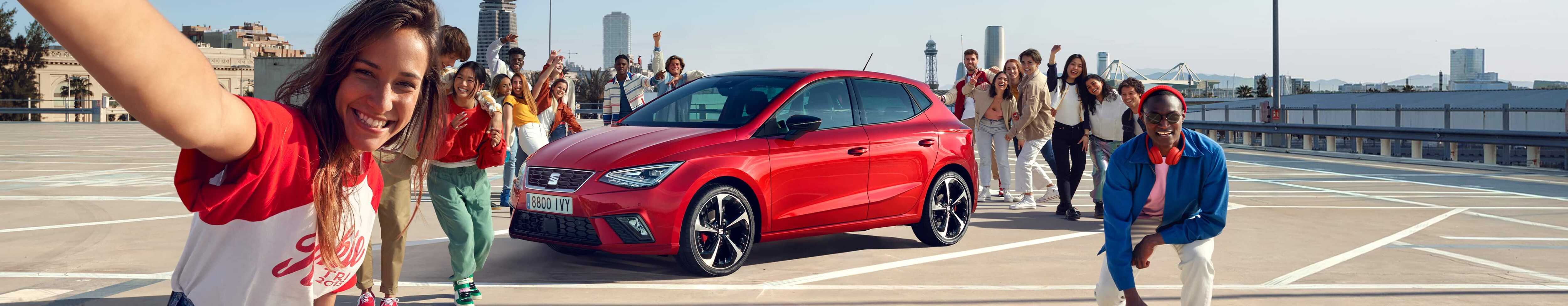 Des amis discutant à côté d’une SEAT Ibiza de couleur desire red